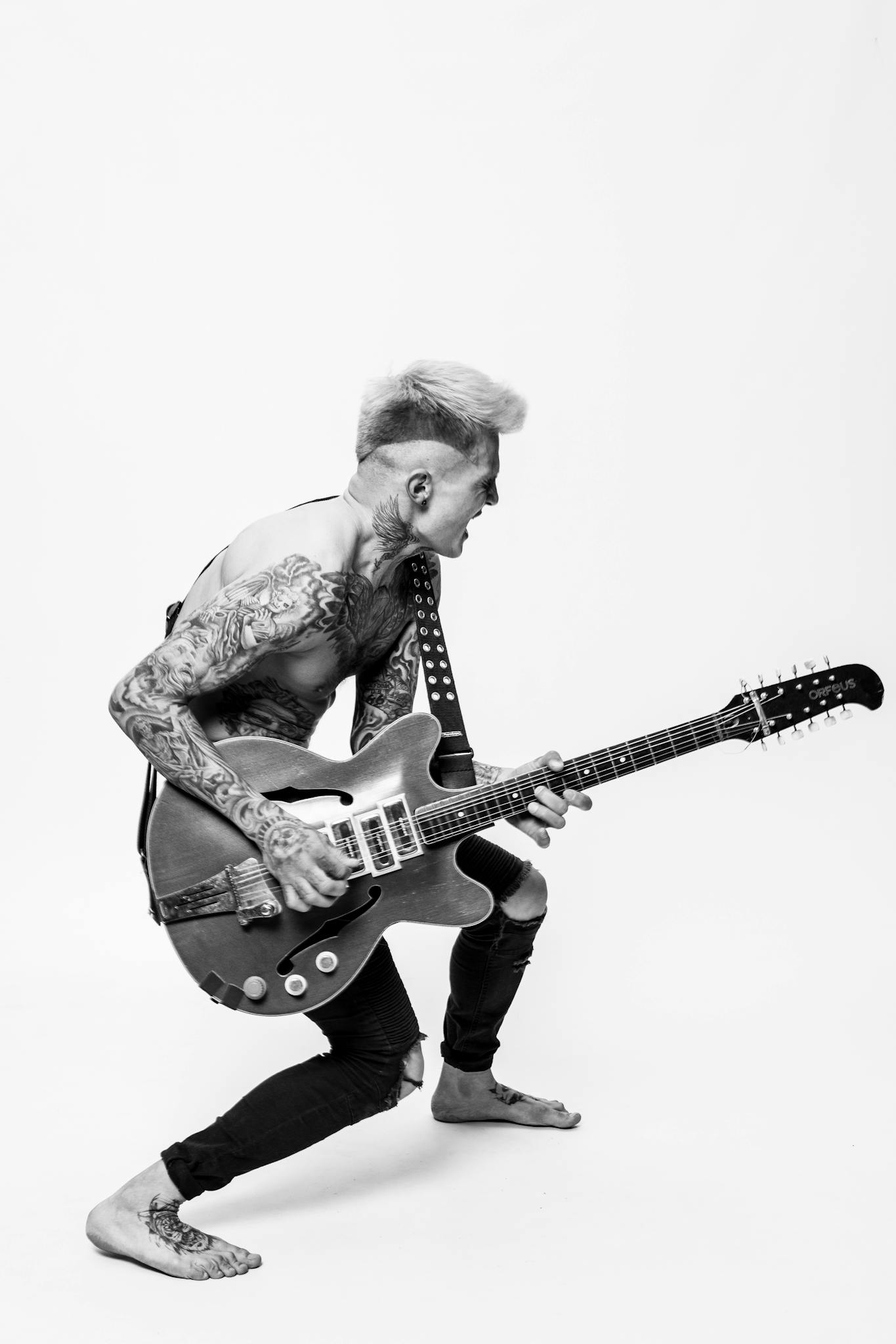 Dynamic shot of a tattooed guitarist passionately playing in black and white.