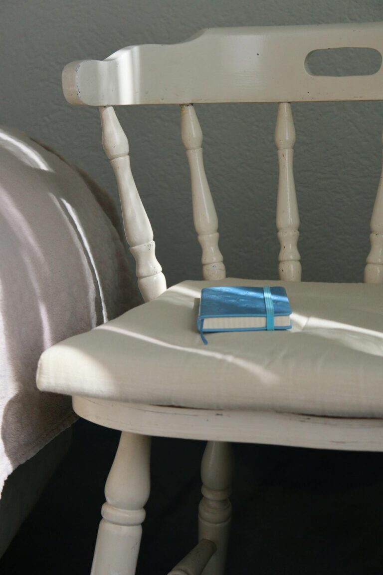 A white chair in sunlight with a blue notebook, illustrating comfort and simplicity.